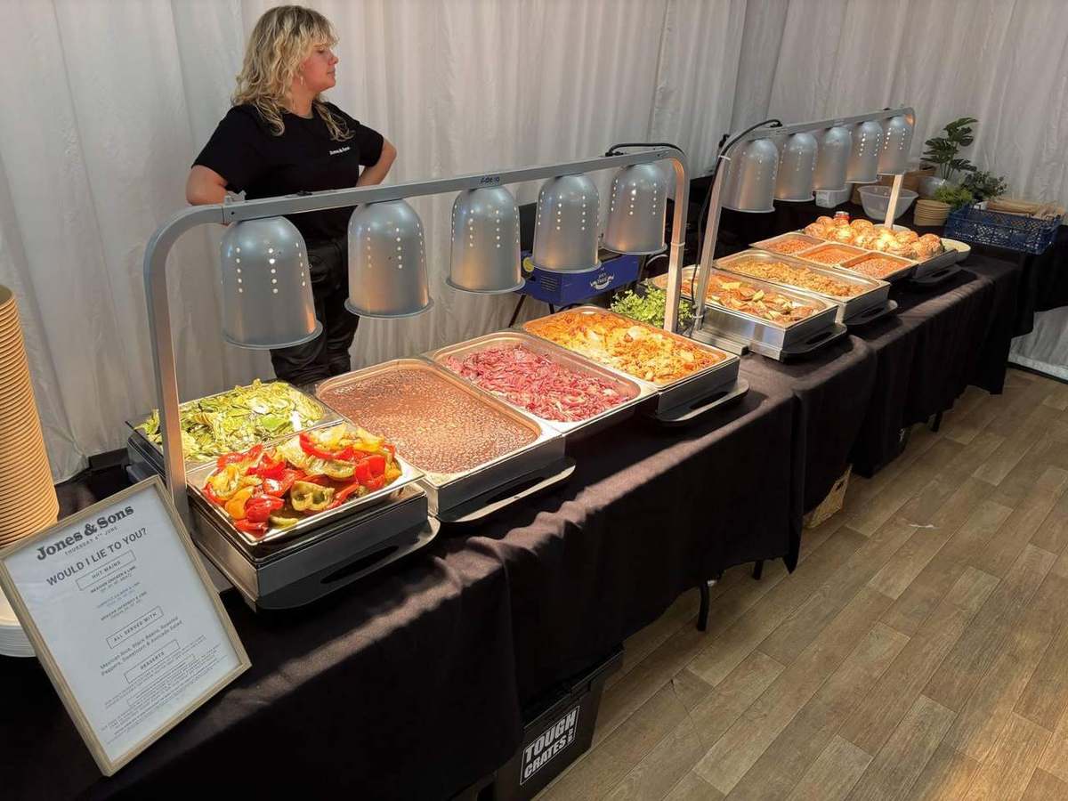 Hot buffet service with heat lamps and a Jones & Sons team member at the pass