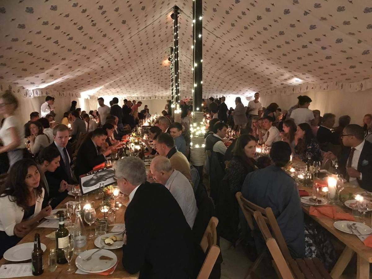 Wedding reception guests seated at long candlelit tables in a marquee