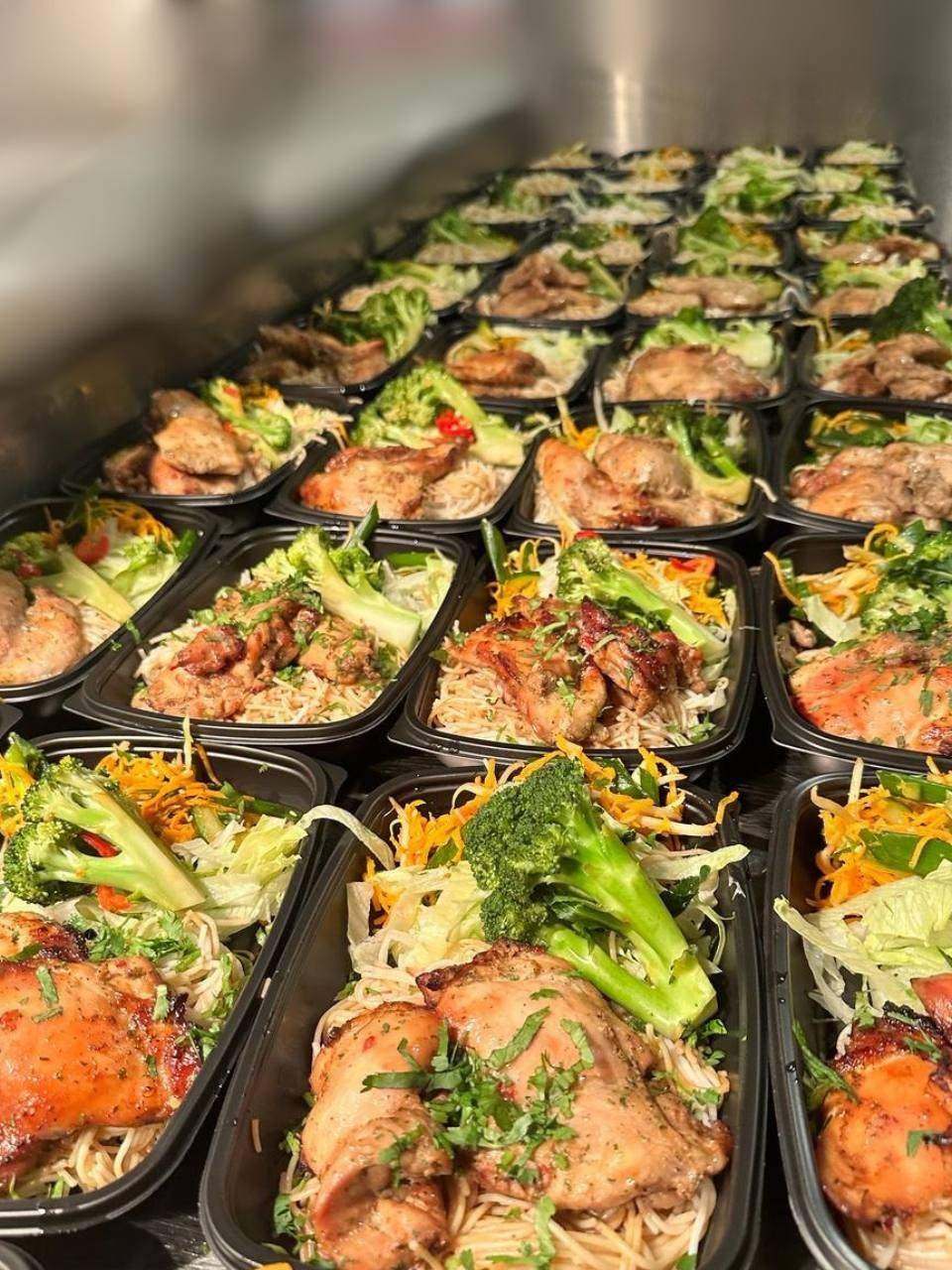 Trays of Hot Box chicken and noodle meals lined up in the kitchen