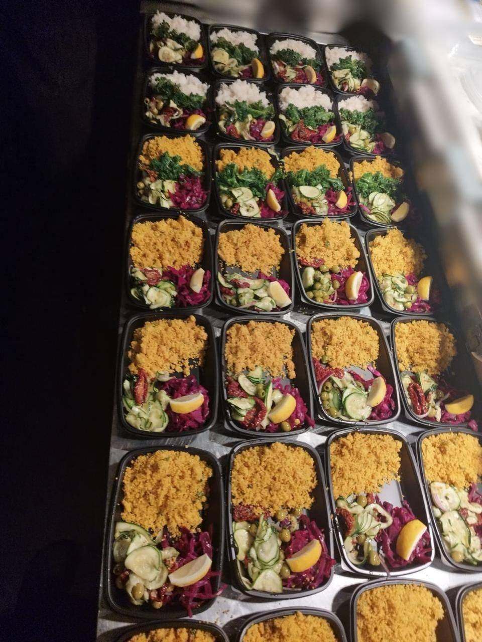 Trays of individual meals with grains and slaw being packed